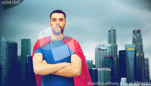 Image of man in red superhero cape over city background