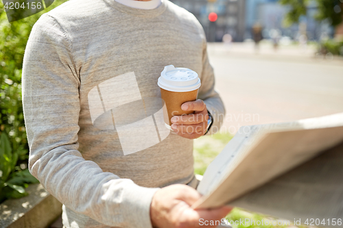 Image of senior man with coffee reading newspaper outdoors