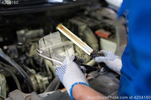 Image of mechanic man with pliers repairing car at workshop