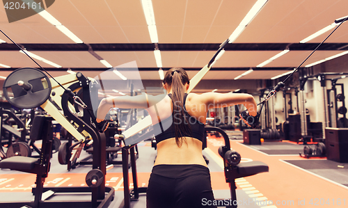 Image of woman flexing muscles on cable machine in gym