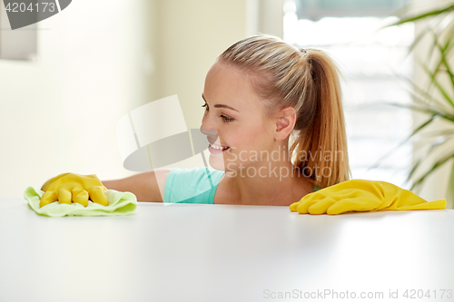 Image of happy woman cleaning table at home