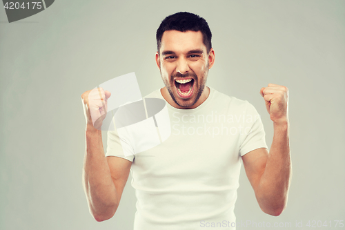 Image of young man celebrating victory over gray