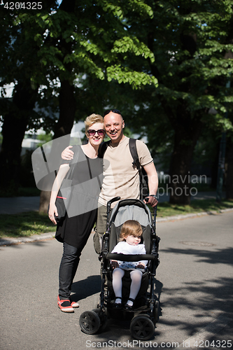 Image of couple with baby pram in summer park