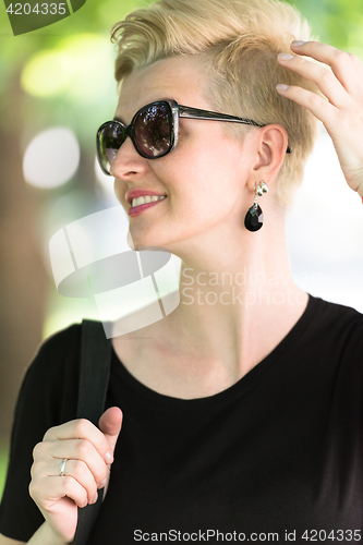 Image of young woman with short blond hair and sunglasses