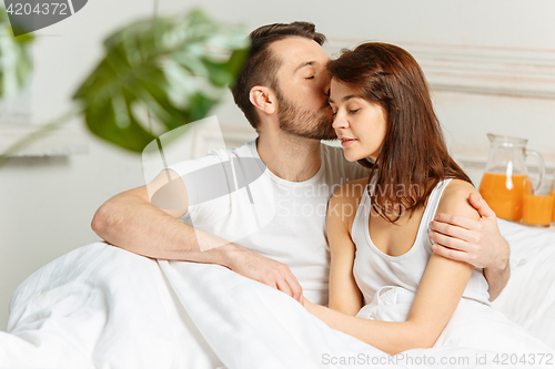 Image of Young adult heterosexual couple lying on bed in bedroom