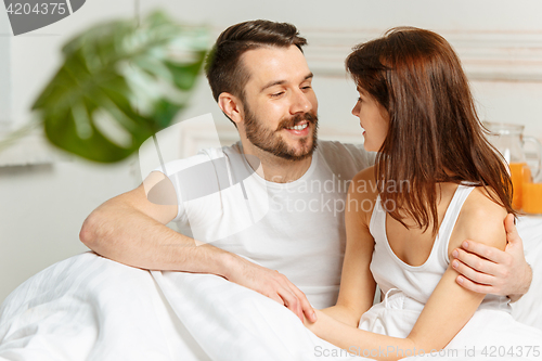 Image of Young adult heterosexual couple lying on bed in bedroom