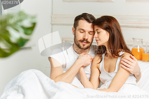 Image of Young adult heterosexual couple lying on bed in bedroom