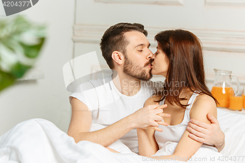 Image of Young adult heterosexual couple lying on bed in bedroom