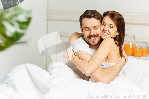 Image of Young adult heterosexual couple lying on bed in bedroom