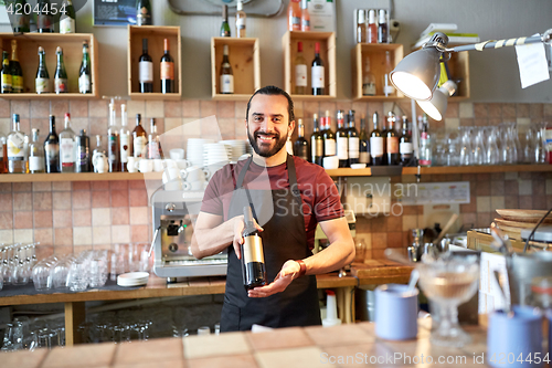 Image of happy man or waiter with bottle of red wine at bar