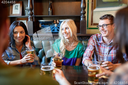 Image of happy friends drinking beer at bar or pub