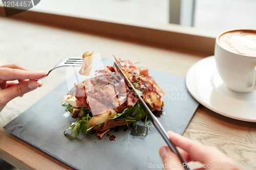 Image of woman eating prosciutto ham salad at restaurant