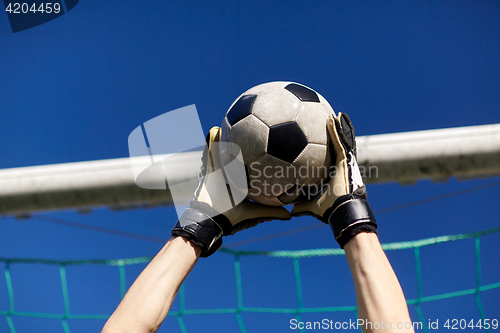 Image of goalkeeper with ball at football goal over sky