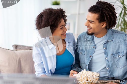 Image of smiling couple with popcorn watching tv at home