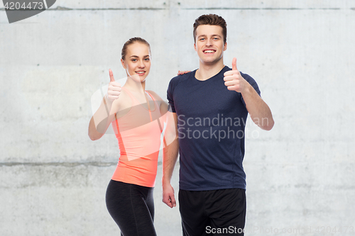 Image of happy sportive man and woman showing thumbs up