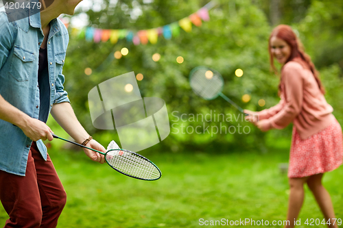 Image of happy couple playing badminton at summer garden