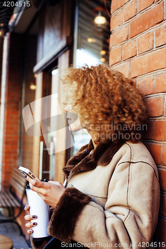 Image of young pretty african american women drinking coffee outside in c