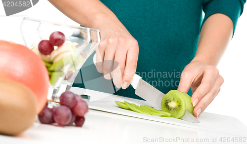 Image of Cook is chopping kiwi for fruit dessert