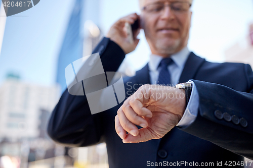 Image of senior businessman calling on smartphone in city