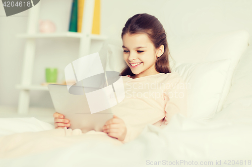 Image of happy girl lying in bed with tablet pc at home