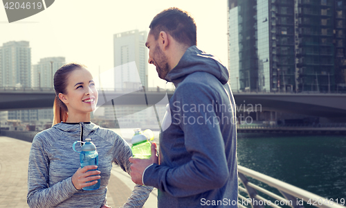 Image of smiling couple with bottles of water in city