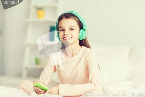 Image of girl sitting on bed with smartphone and headphones