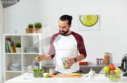 Image of man with blender cup cooking food at home kitchen