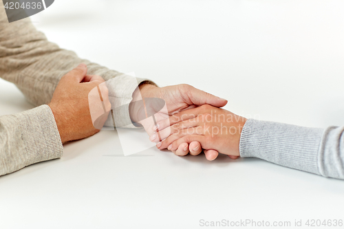 Image of close up of old man and young woman holding hands