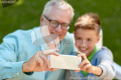 Image of old man and boy taking selfie by smartphone