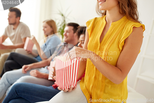 Image of close up of happy friends eating popcorn at home