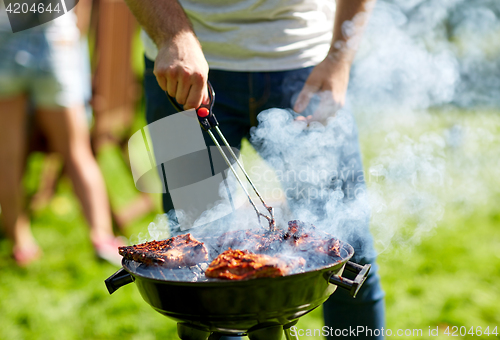 Image of man cooking meat on barbecue grill at summer party