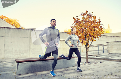 Image of couple doing lunge exercise on city street