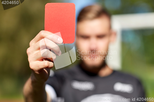 Image of referee hands with red card on football field