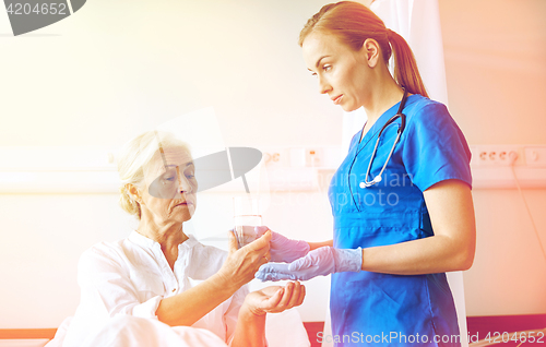 Image of nurse giving medicine to senior woman at hospital