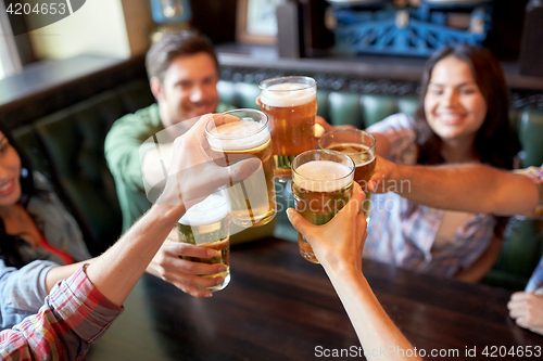 Image of happy friends drinking beer at bar or pub