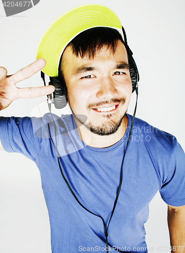 Image of young asian man in hat and headphones listening music on white b