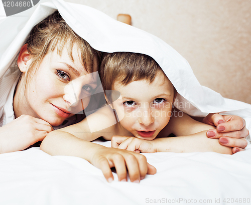 Image of young blond woman with little boy in bed, mother and son, happy family 