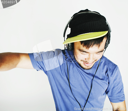 Image of young asian man in hat and headphones listening music on white b