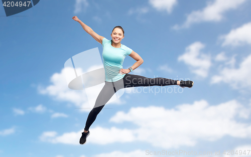 Image of happy sporty young woman jumping in blue sky