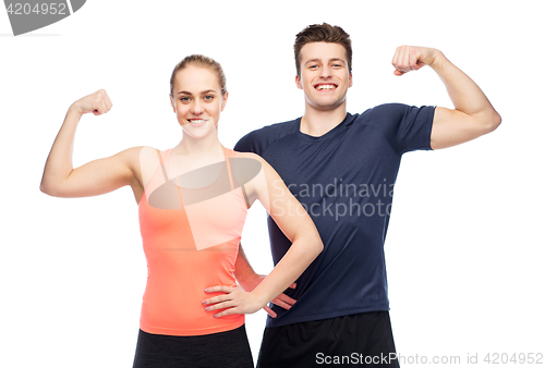 Image of happy sportive man and woman showing biceps power