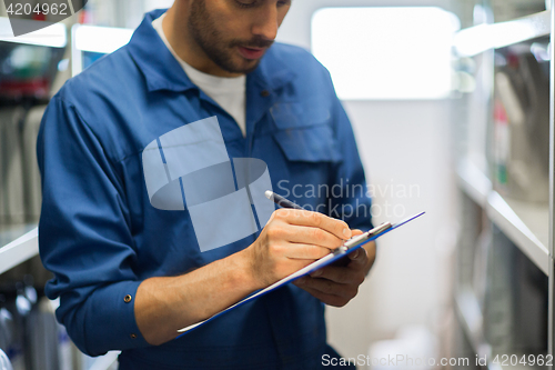 Image of auto mechanic with clipboard at car workshop