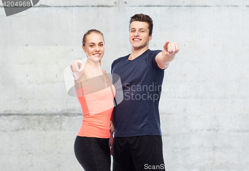 Image of happy sportive man and woman pointing finger