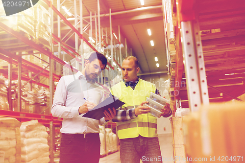 Image of worker and businessmen with clipboard at warehouse