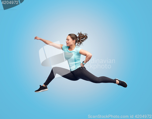 Image of happy sporty young woman jumping in fighting pose