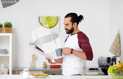 Image of man reading newspaper and eating at home kitchen