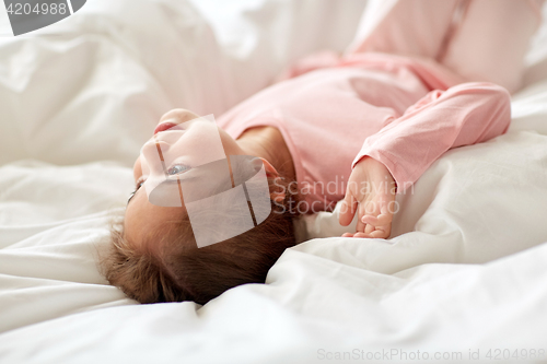 Image of happy little girl lying in bed at home