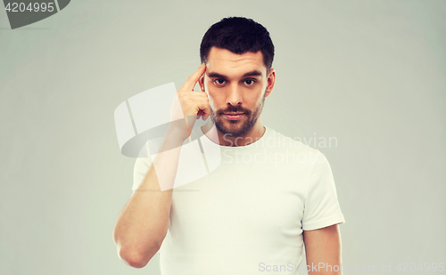 Image of man with finger at temple over gray background