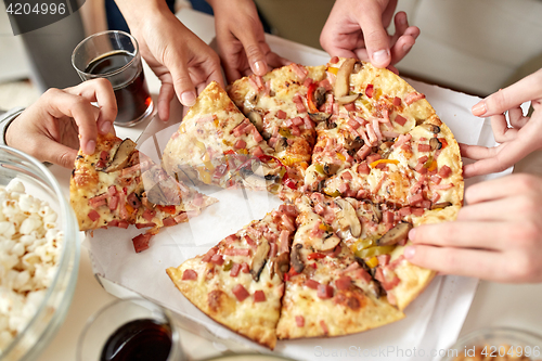 Image of close up of people taking pizza slices from box