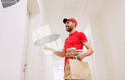 Image of delivery man with coffee and food ringing doorbell