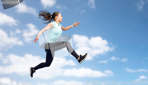 Image of happy sporty young woman jumping in blue sky